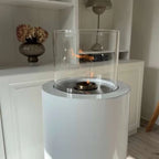 ScandiFlames Dualis bioethanol fireplace with a white fireplace body and a cylindrical safety glass