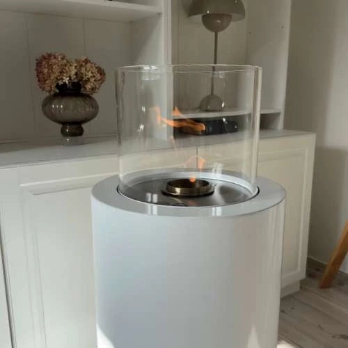 ScandiFlames Dualis bioethanol fireplace with a white fireplace body and a cylindrical safety glass